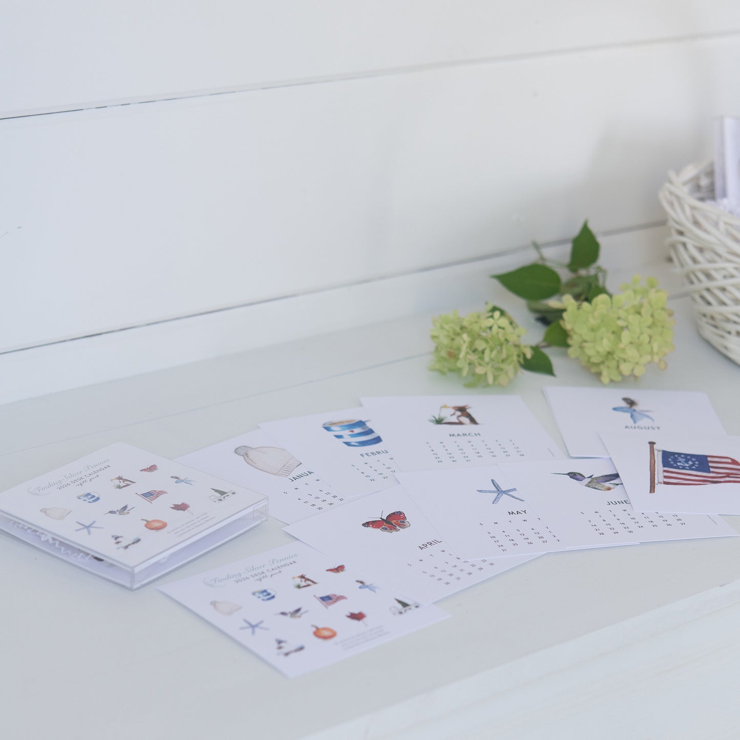 Calendar with illustrations on a white surface with flowers in the background