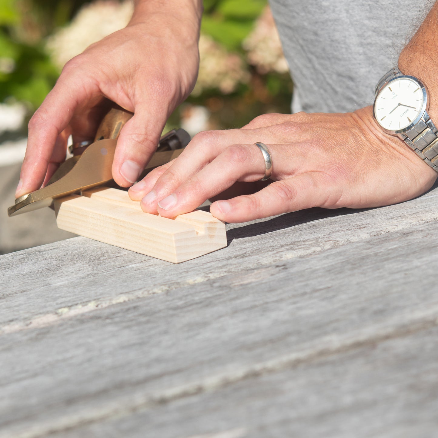 Person using a brass plane on a wooden stand.
