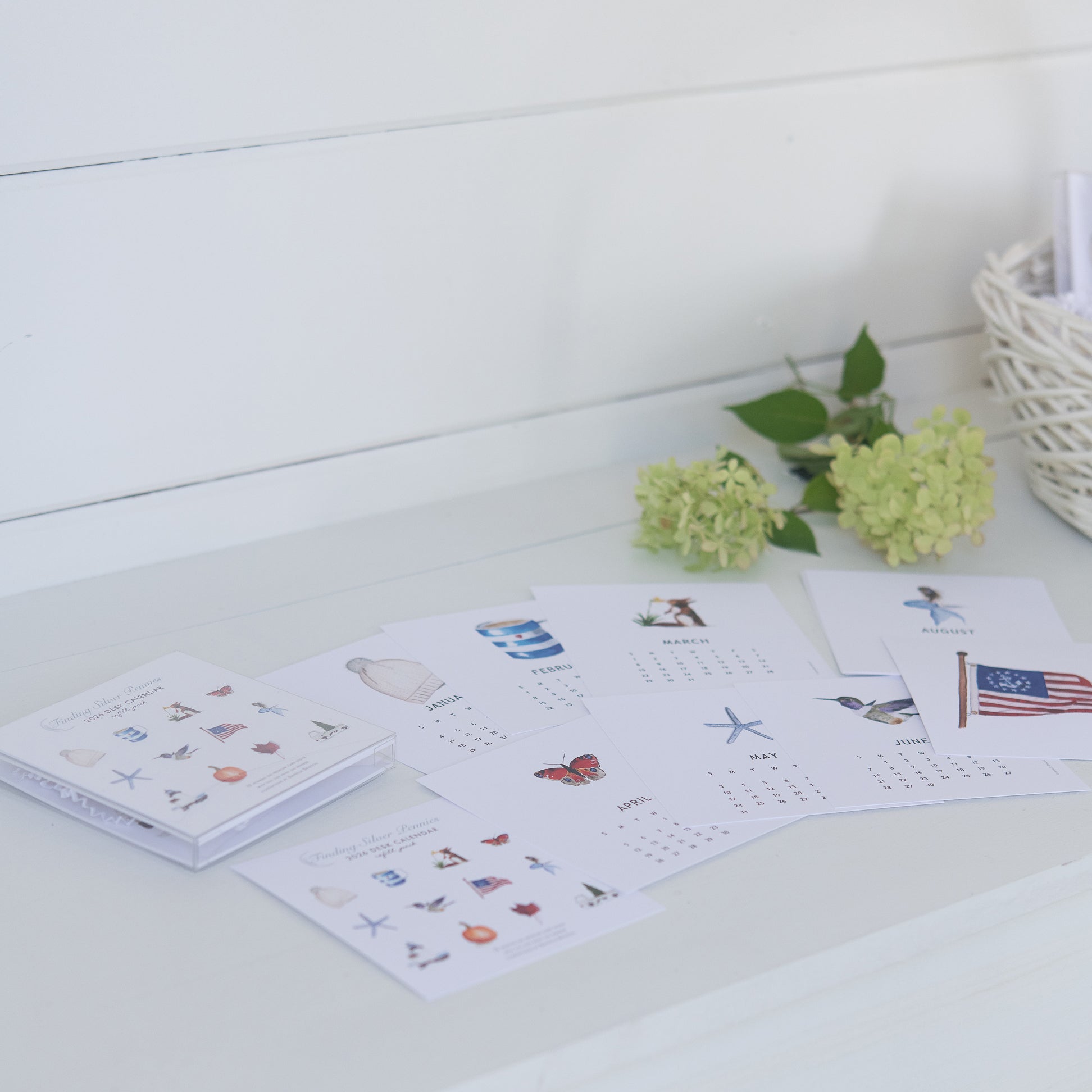 Calendar with illustrations on a white surface with flowers in the background