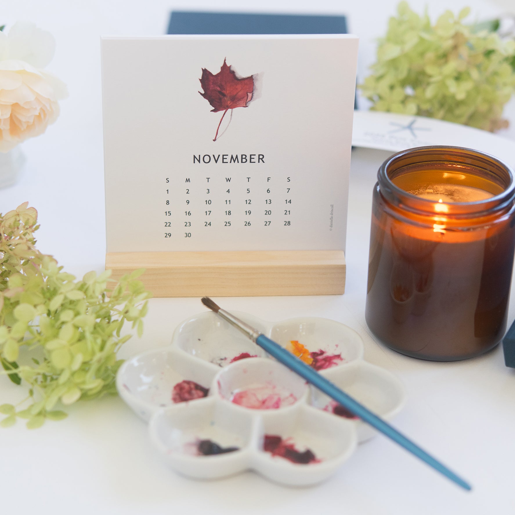 Calendar for November with a candle and paint palette on a table