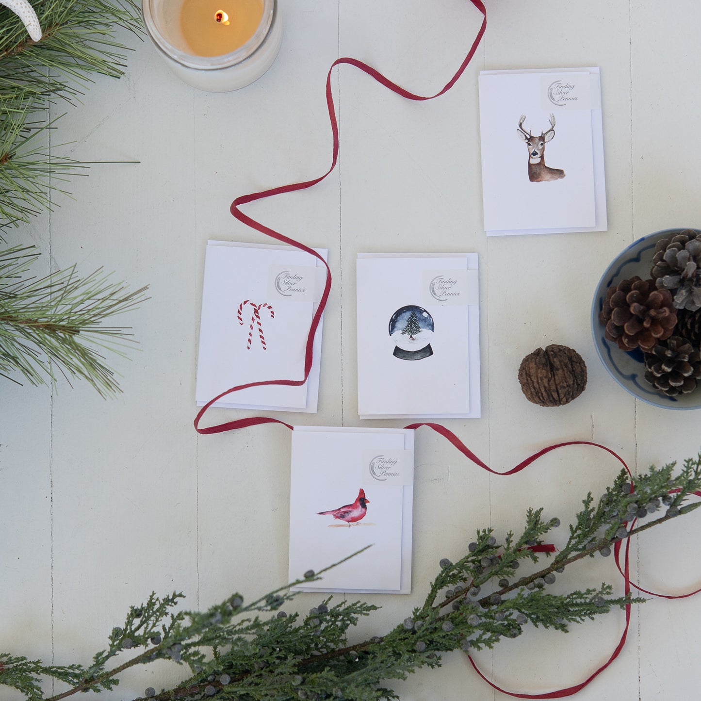 Set of Christmas-themed cards with decorative ribbons and greenery on a white surface