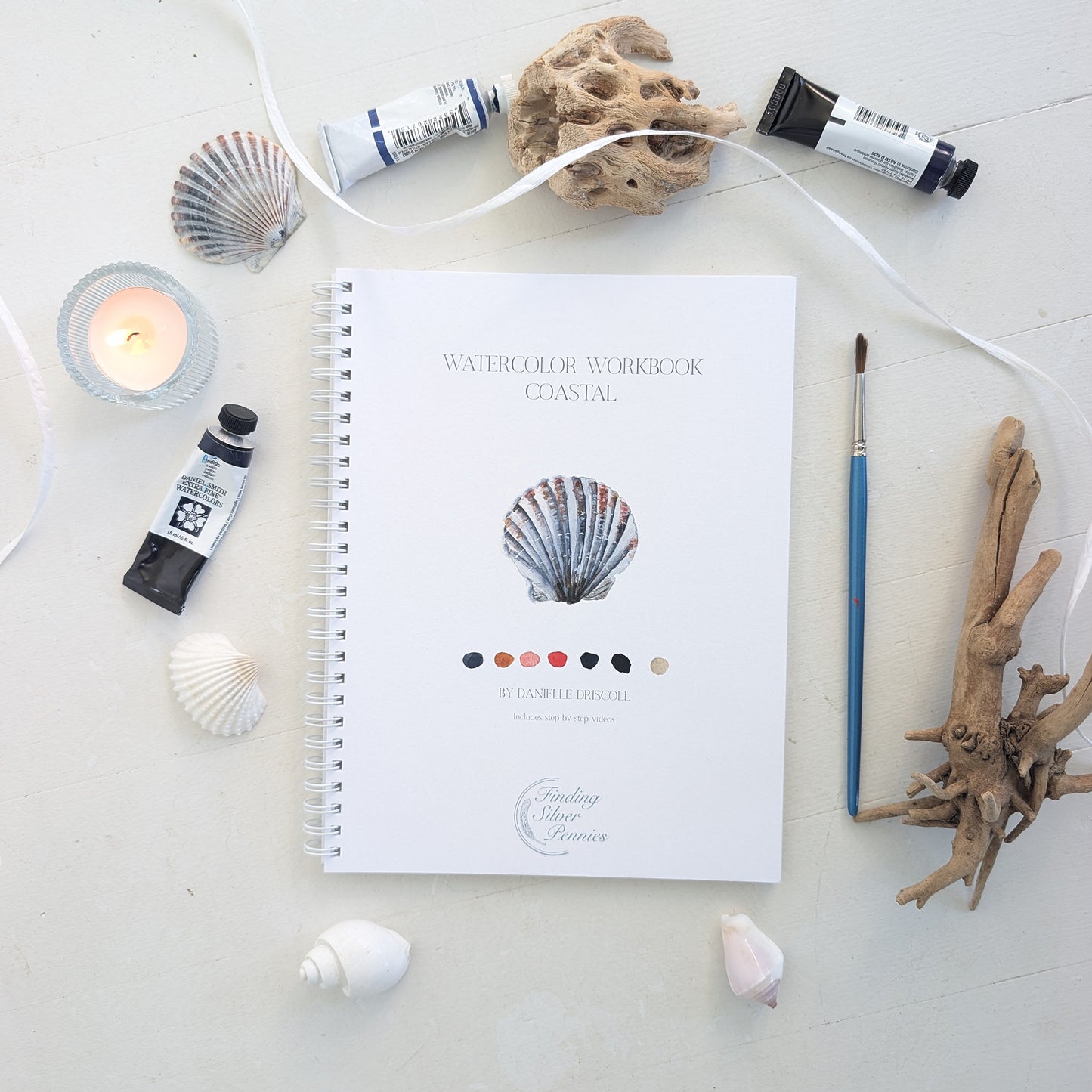 Watercolor workbook with coastal theme on a light surface with art supplies