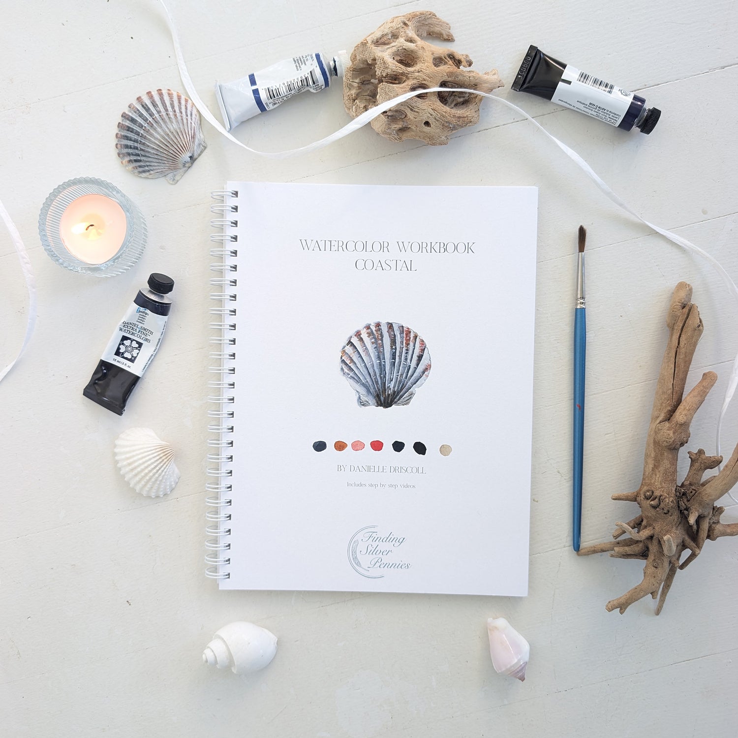 Watercolor workbook with coastal theme on a light surface with art supplies