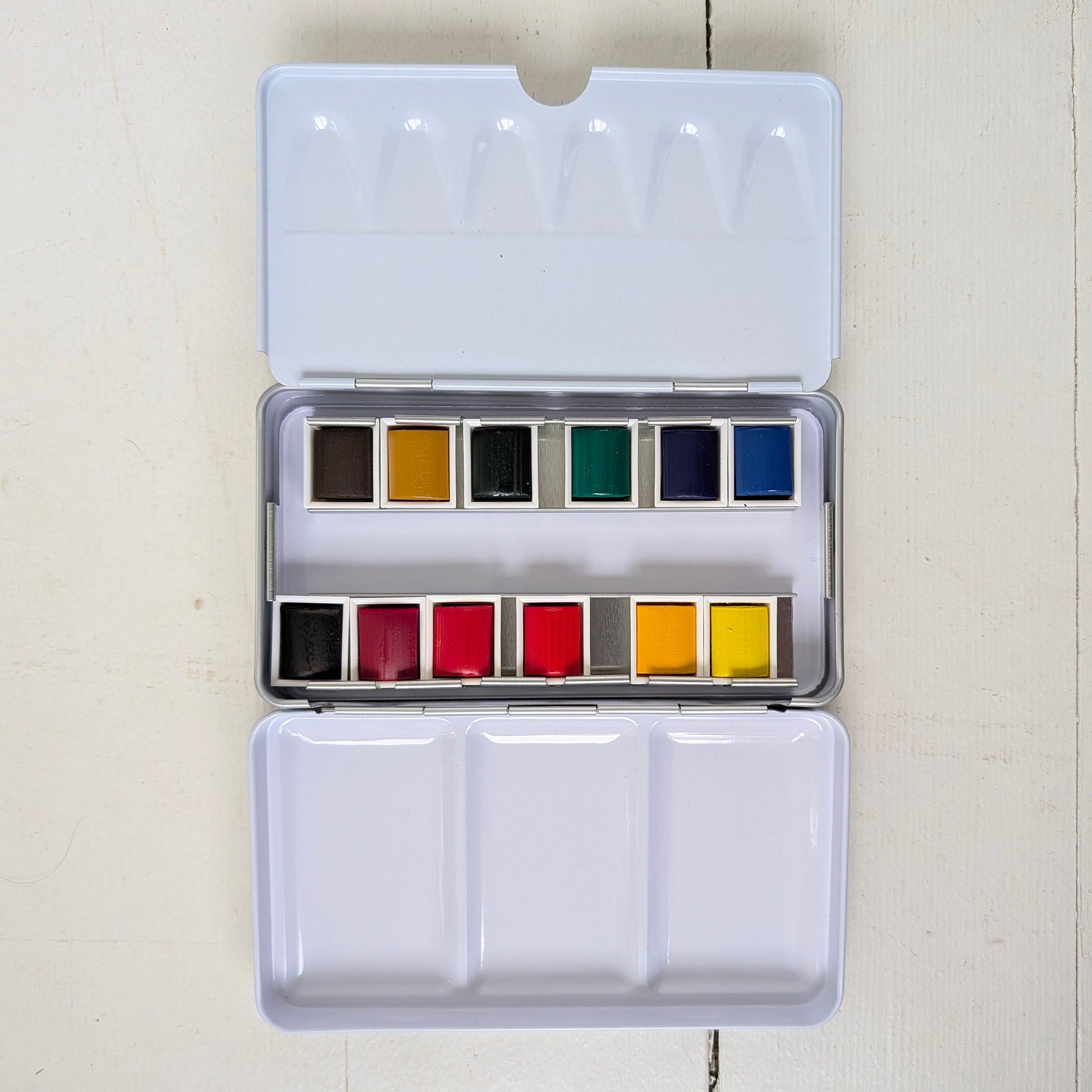Set of watercolor paints in a metal case on a light background