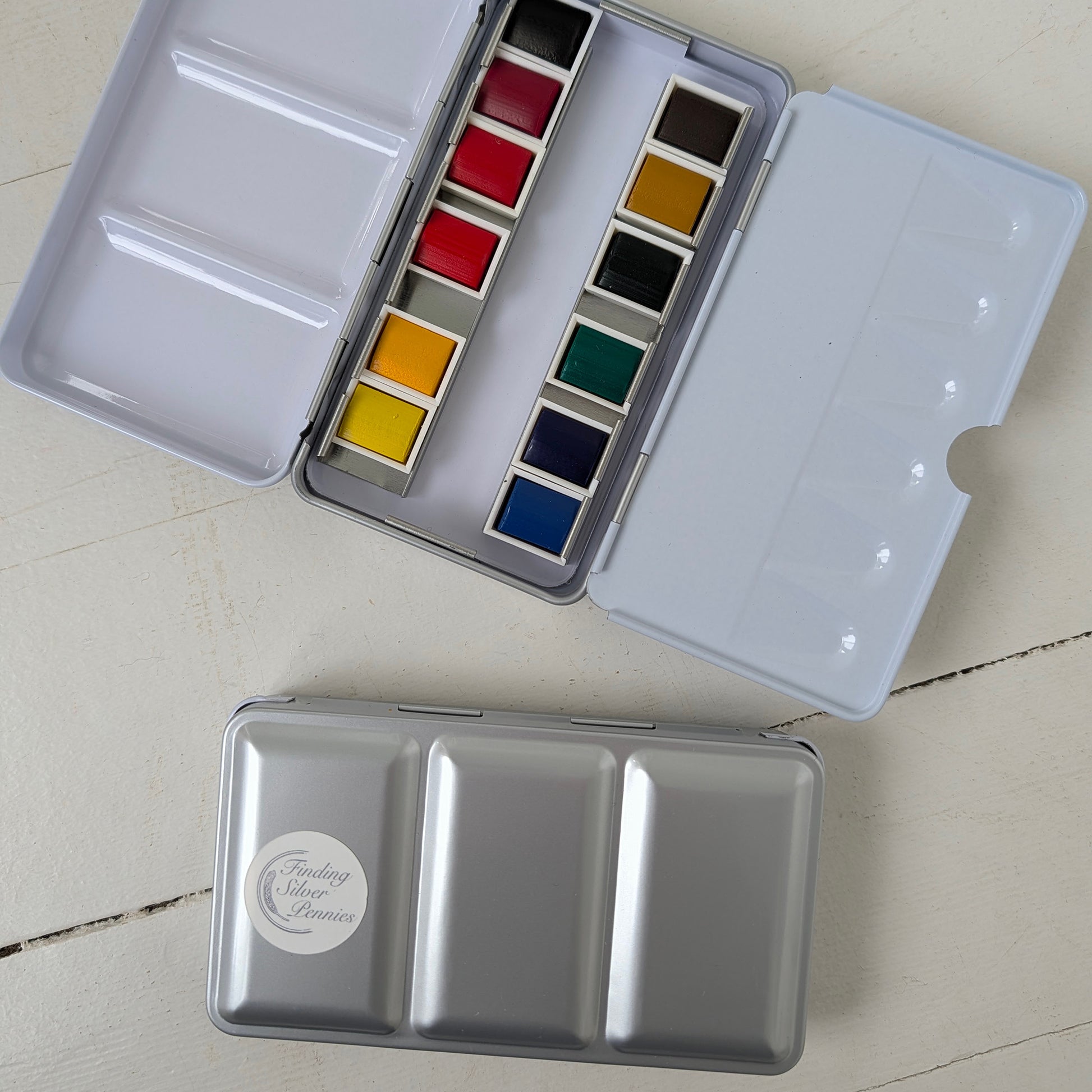 Open watercolor set with colorful paint pans on a light surface