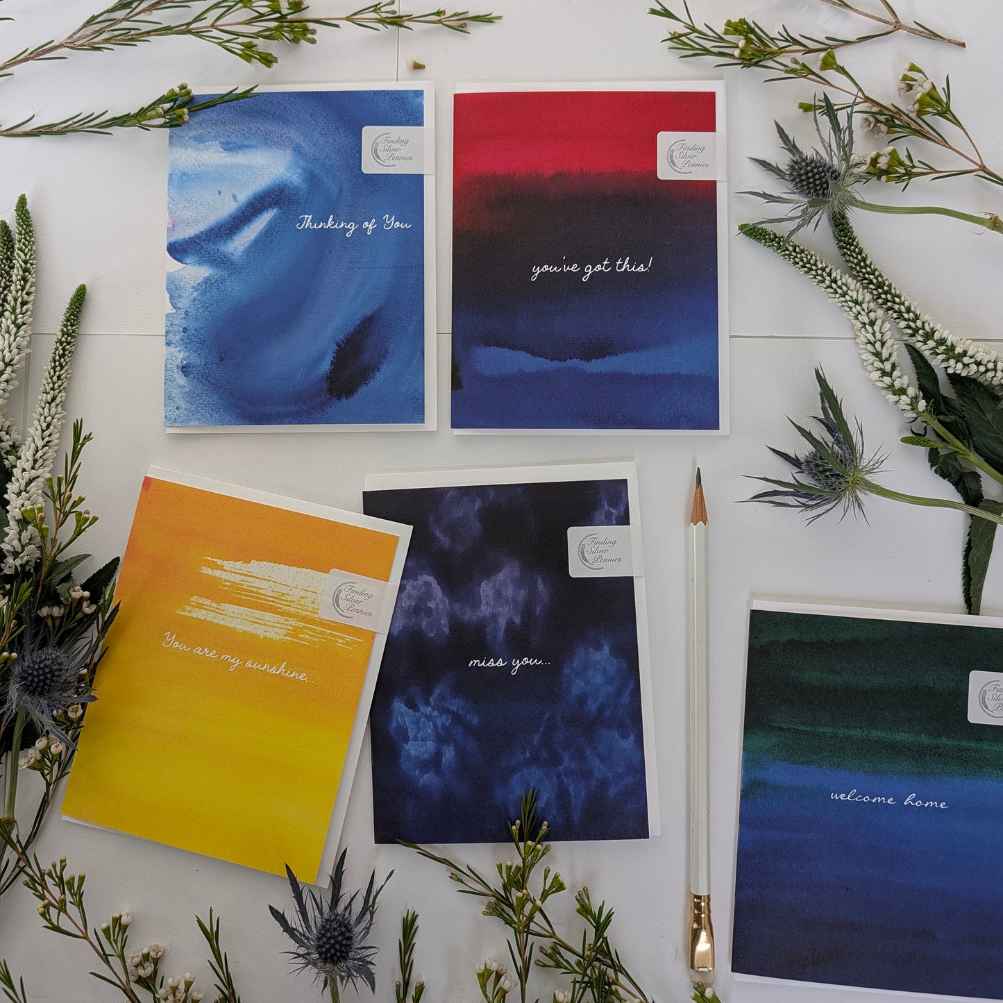 Collection of greeting cards with text on a white surface with greenery