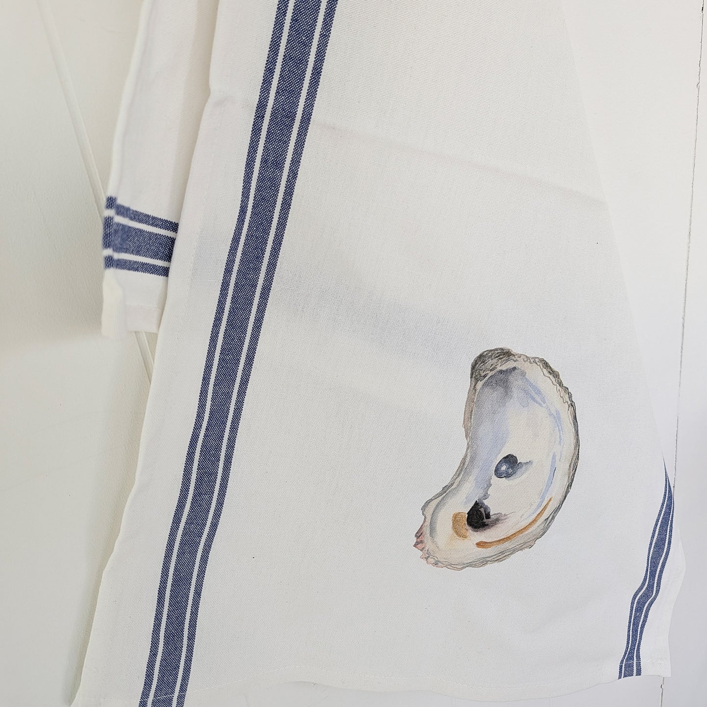 White towel with blue stripes and an oyster design on a white background