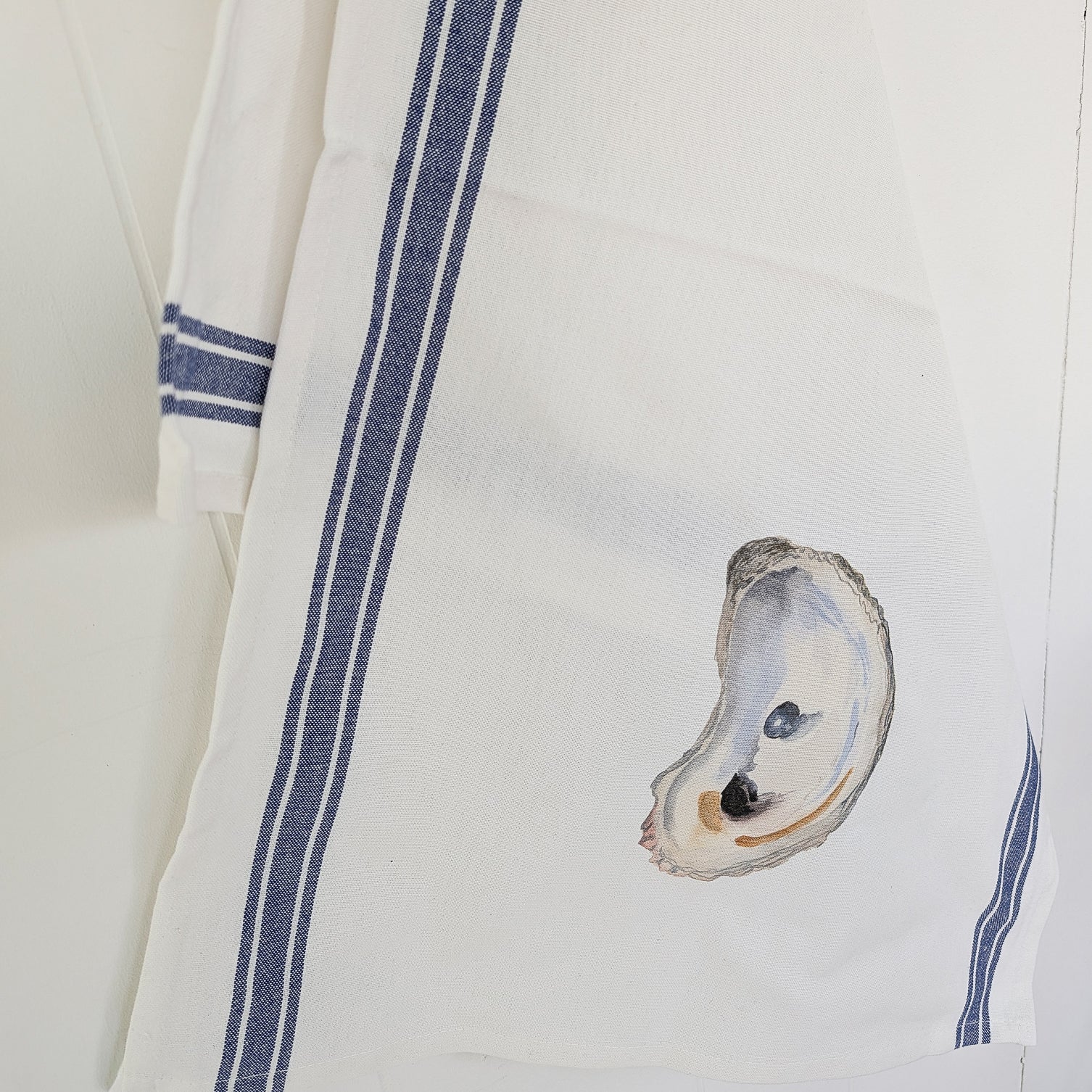 White towel with blue stripes and an oyster design on a white background