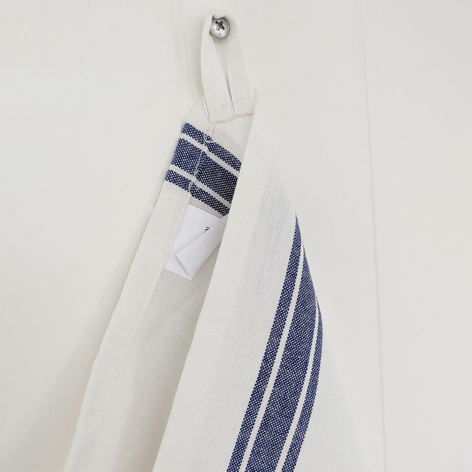 Close-up of a white tea towel with blue striped accents on a white background