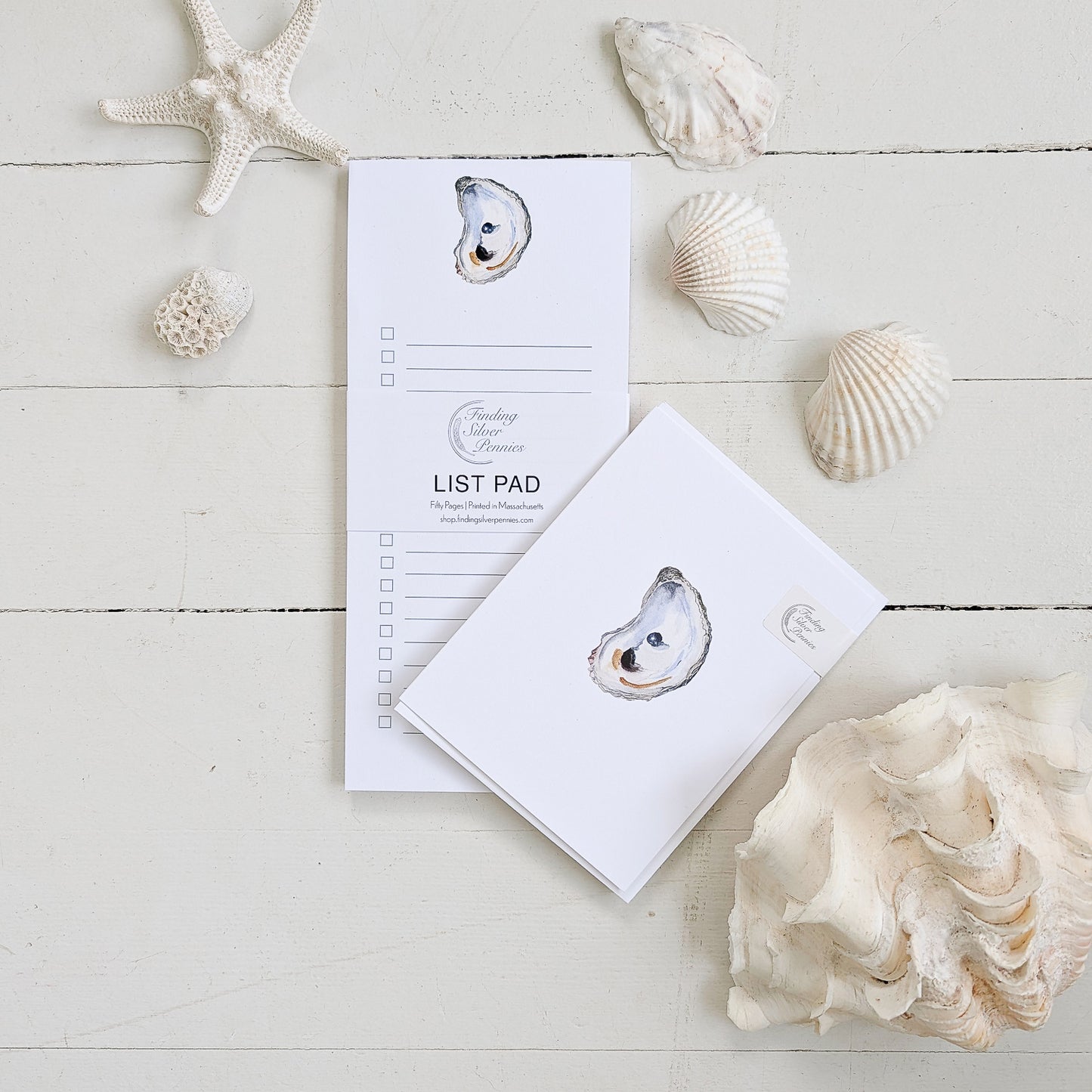Oyster shell-themed list pad and card on a wooden surface with seashells and starfish.