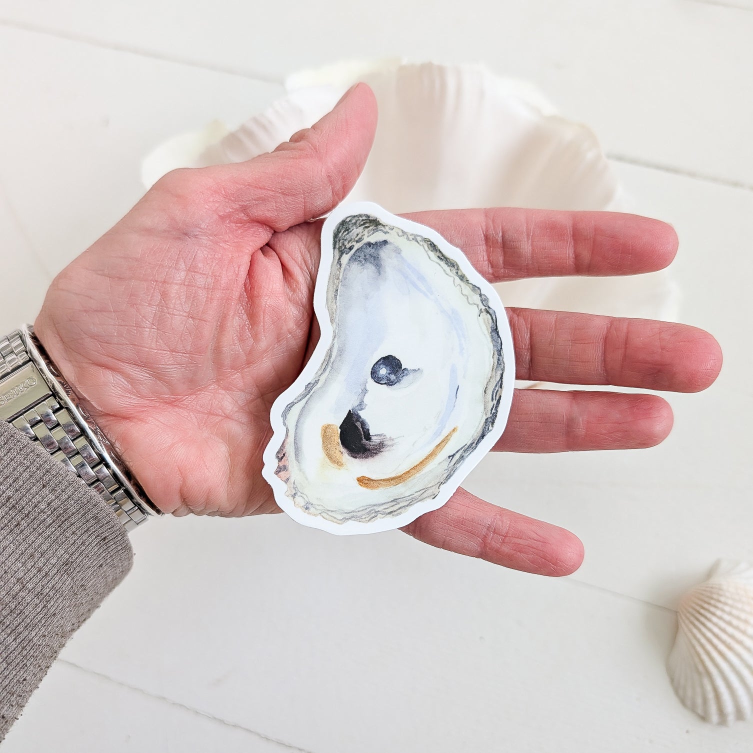 Oyster with Pearl sticker in the palm of a hand
