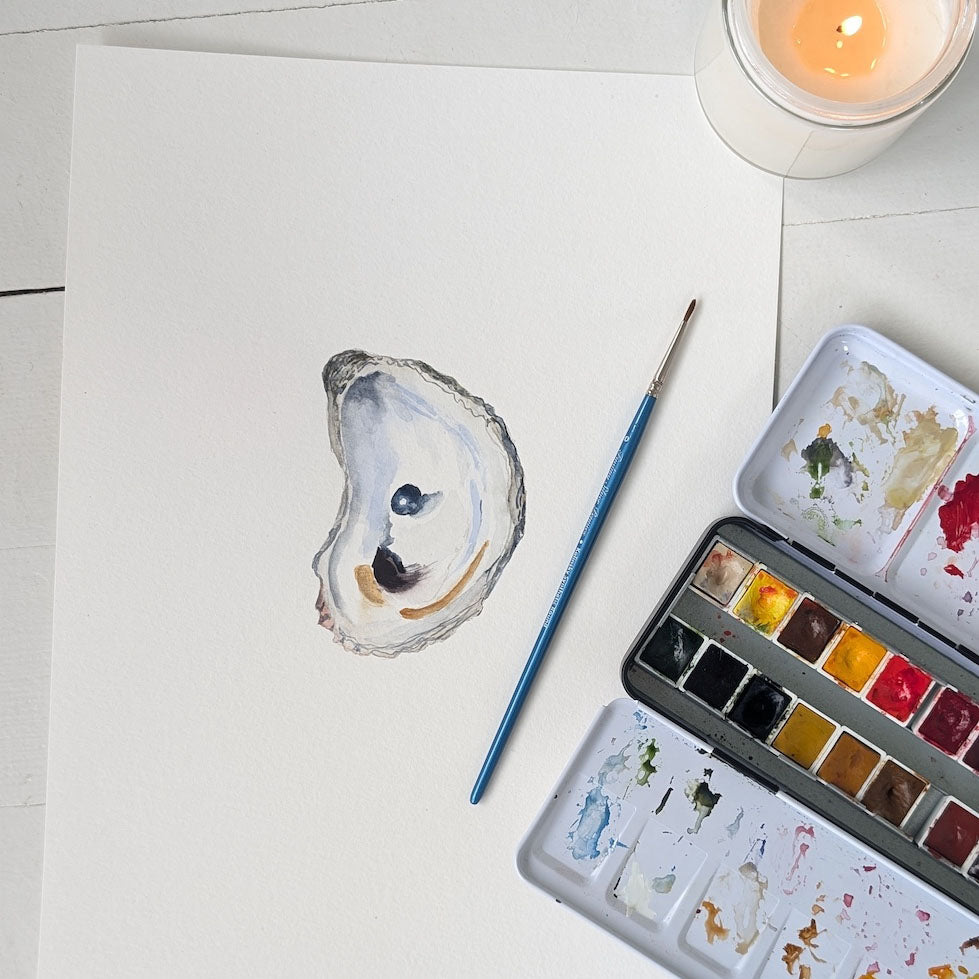Watercolor painting of an oyster shell on a white surface with a watercolor palette and brush.