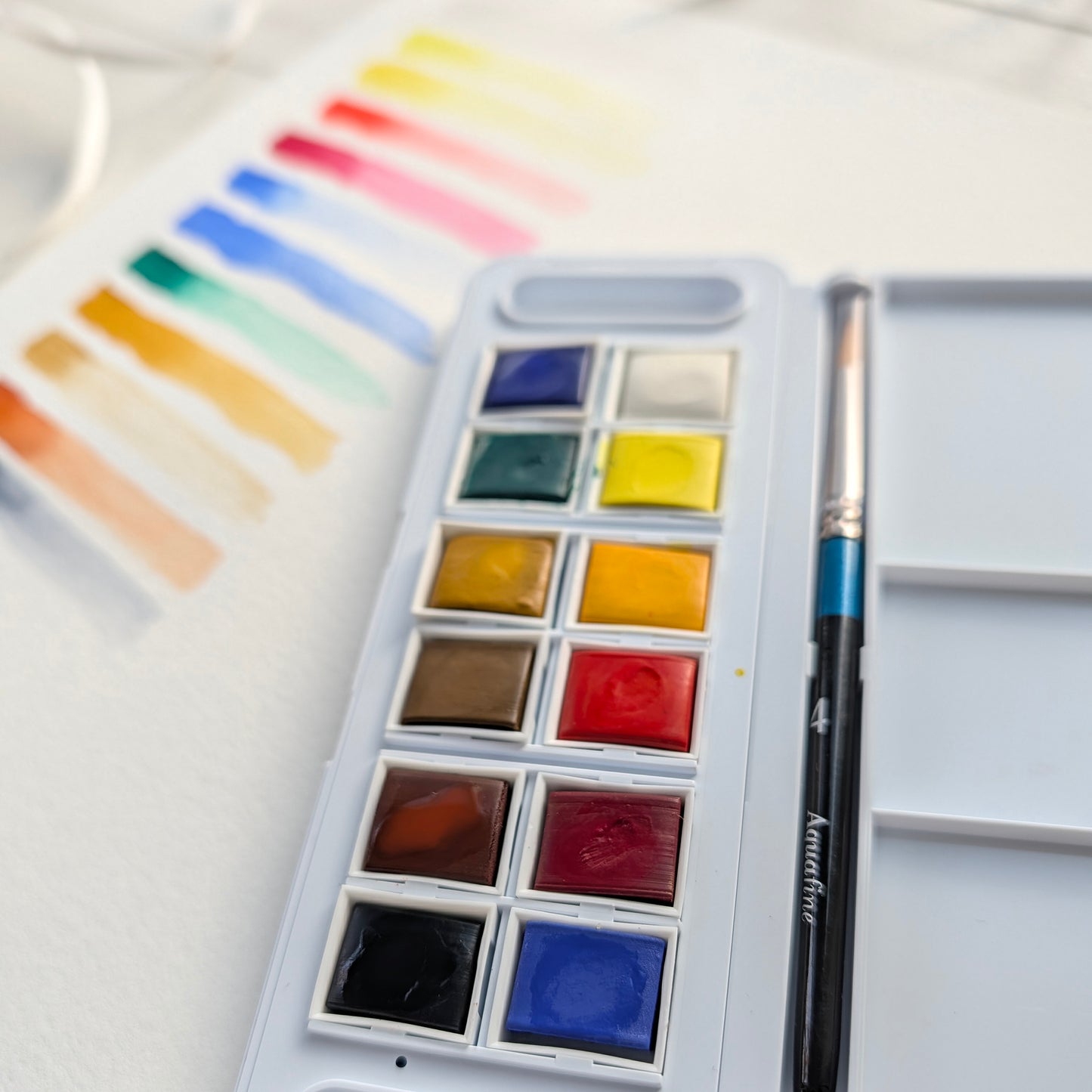 Watercolor paint set with a brush on a white background