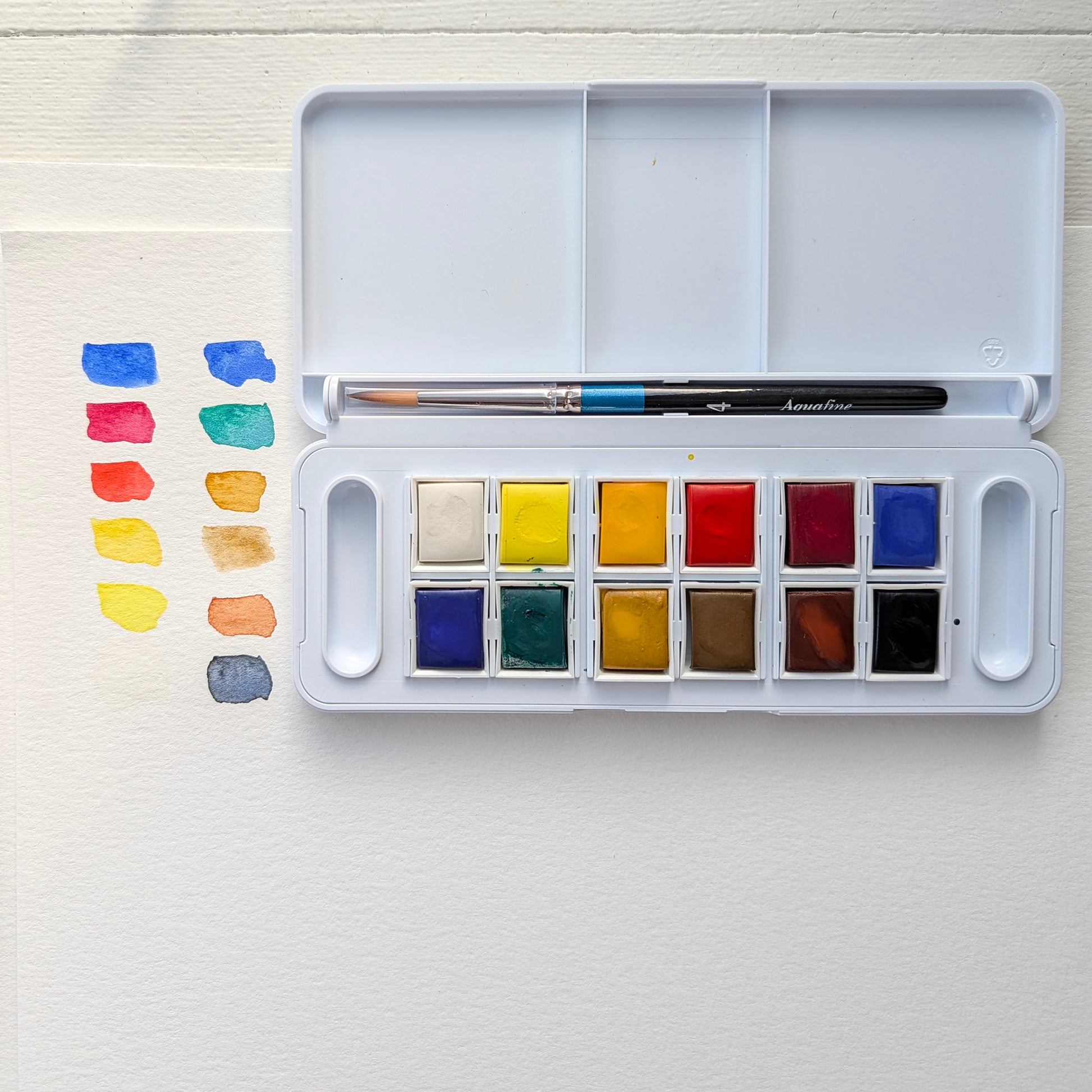 Watercolor paint set with colors swatched on a white surface