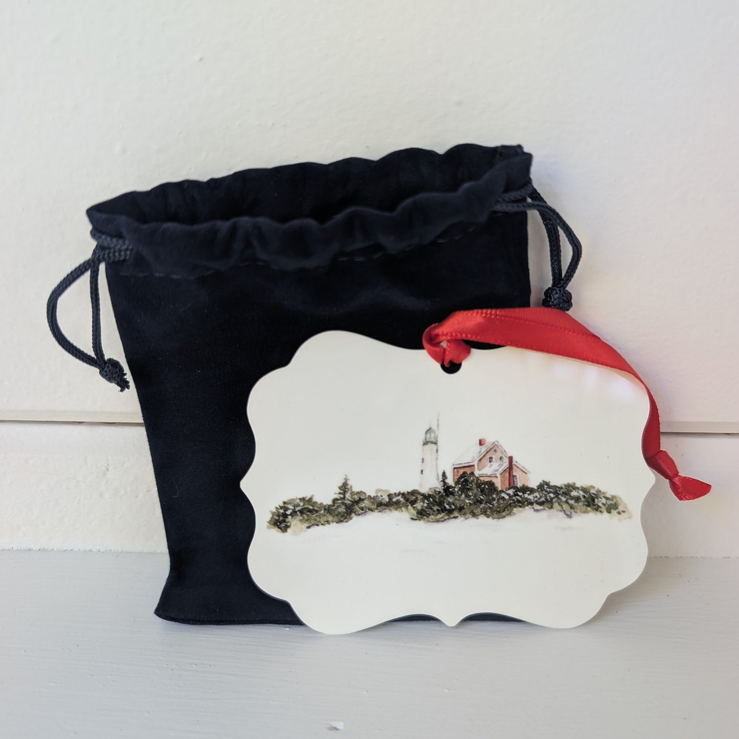 Decorative ornament with lighthouse design on a white background, featuring a blue drawstring bag.