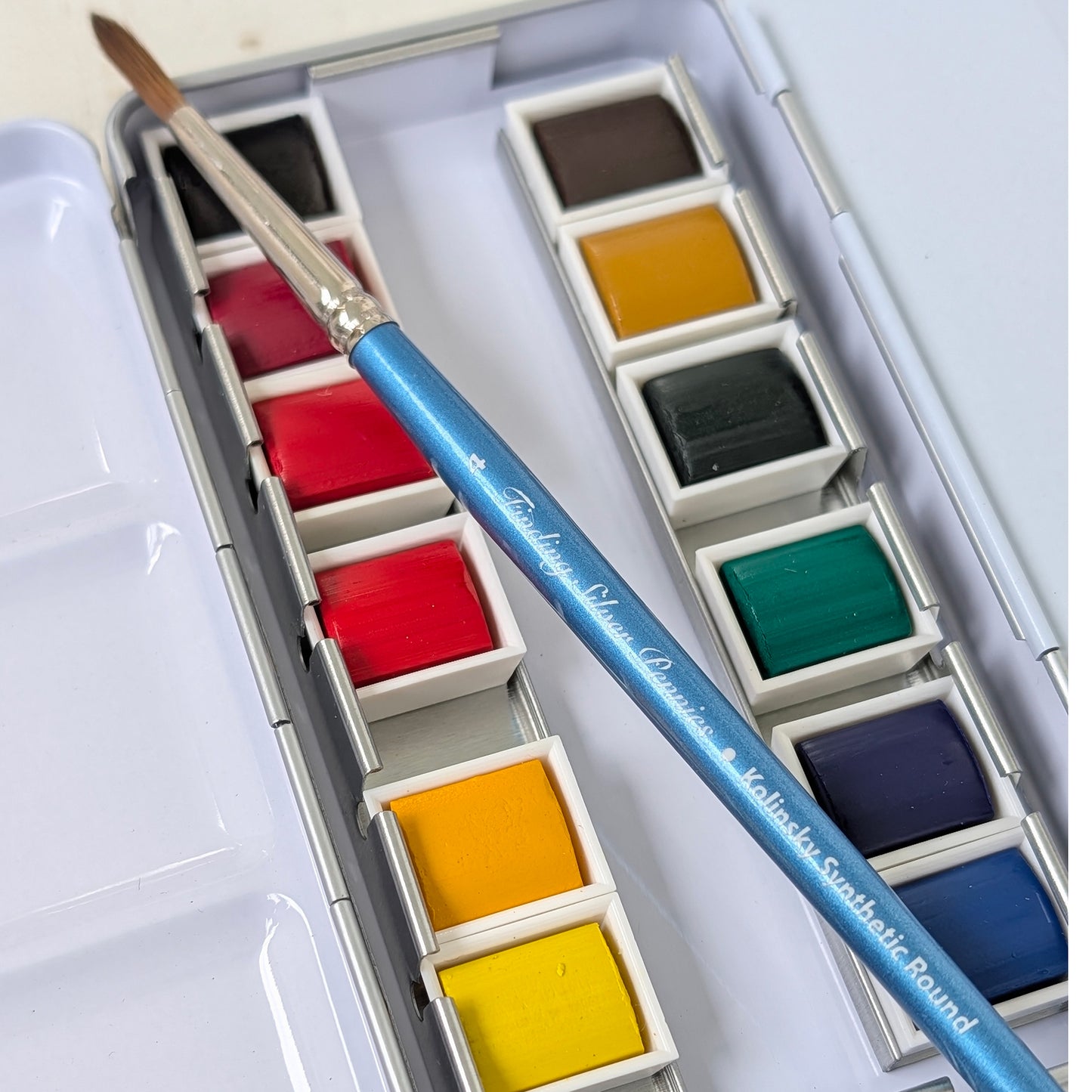 Set of watercolor paints with a brush with tin paint palette